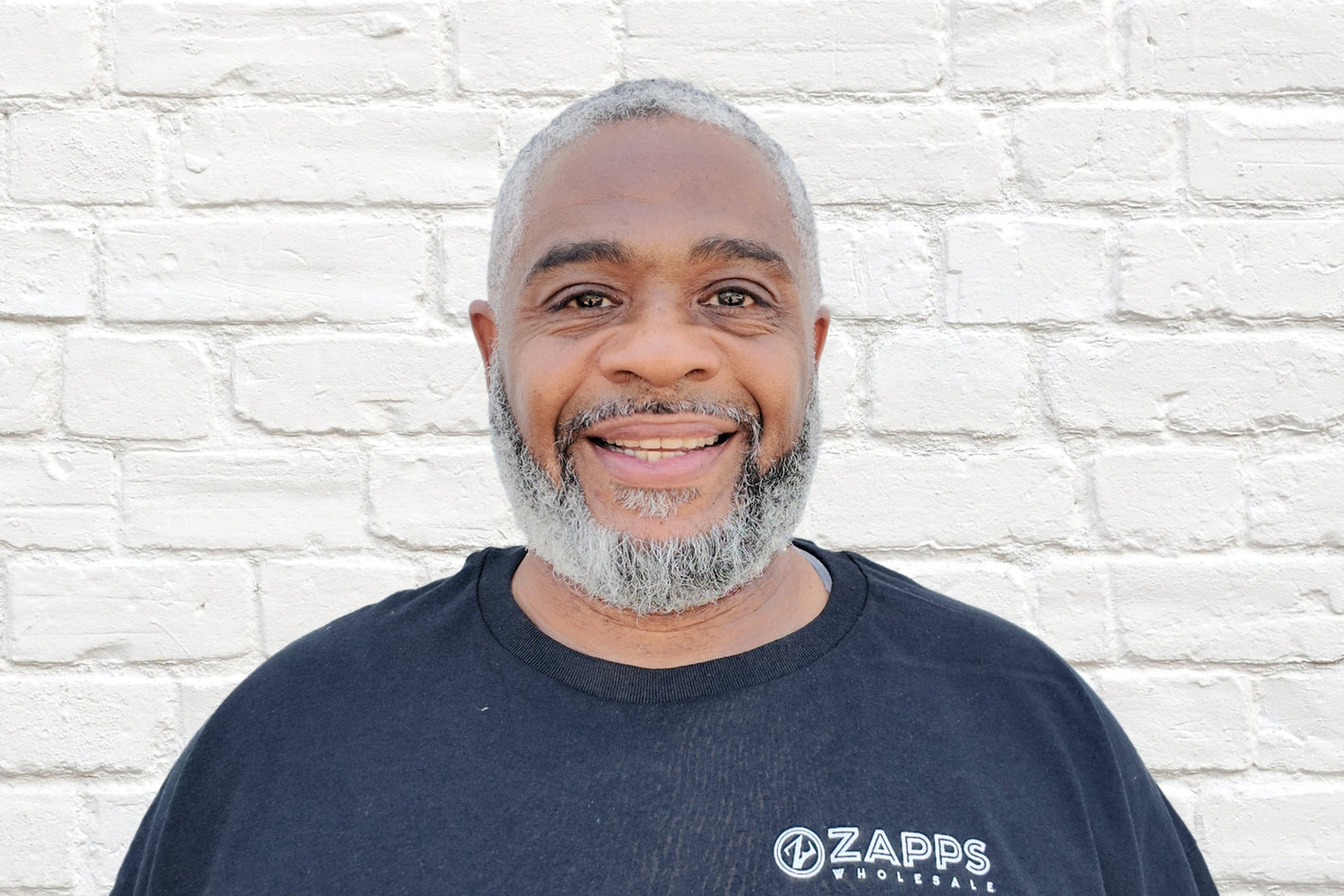 Adrian, Operations Team member of leading wholesale liquidation company in the United States, Zapps Wholesale, poses in North Carolina warehouse.